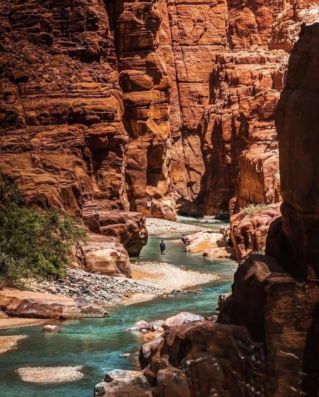 Turquoise water winding through the red sandstone canyon of Wadi Mujib